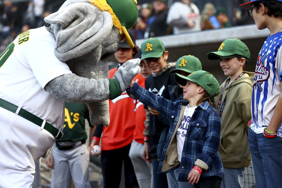 A young Oakland Athletics fan slaps hands with mascot Stomper before the team's baseball spring training game against the Milwaukee Brewers on Friday, March 8, 2024, in Las Vegas.