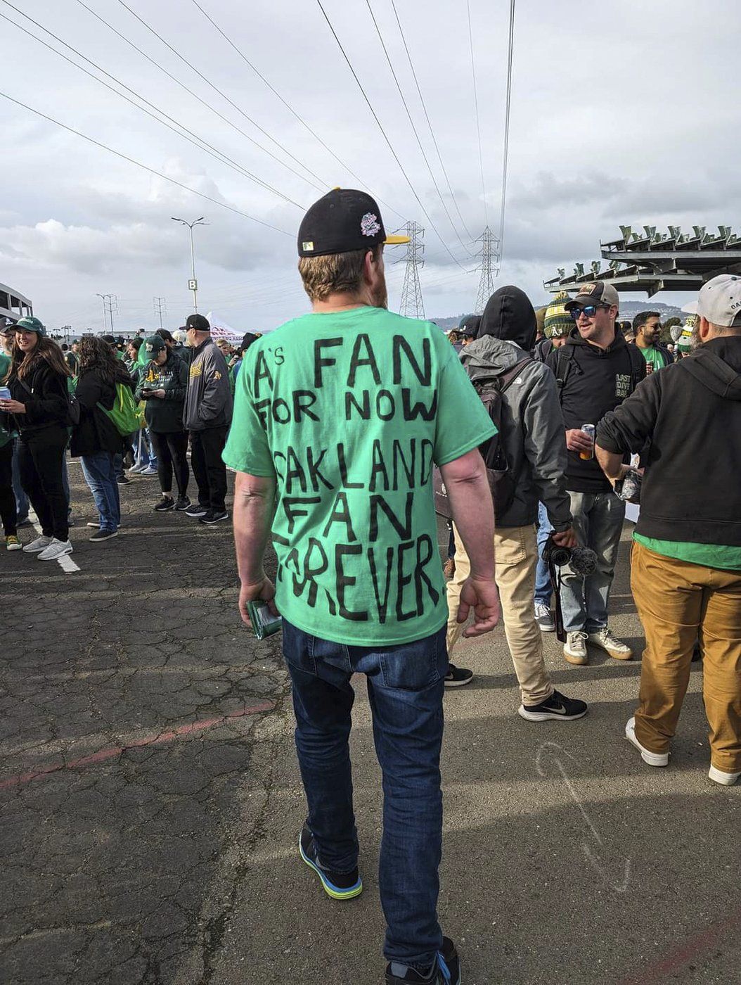 A fan wearing a shirt expressing his dismay with the A's move from Oakland while walking through the Oakland Coliseum parking lot on Opening Night, March 28, 2024, in Oakland, Calif.