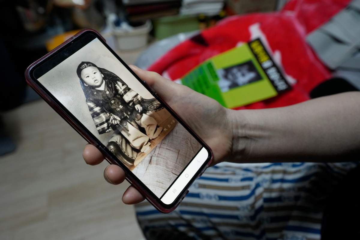 Choi Young-ja holds a smartphone displaying a photo of her son, who went missing in 1975, as she sits in her motel room in Seoul, South Korea, Tuesday, March 5, 2024. (AP Photo/Ahn Young-joon)