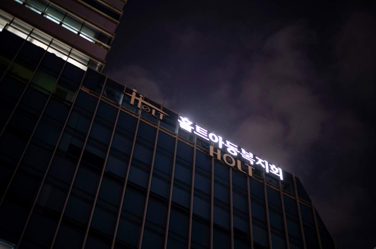 Signs for Holt Children’s Services glow outside the company’s office building at dusk in Seoul, South Korea, Friday, May 24, 2024. (AP Photo/Jae C. Hong)