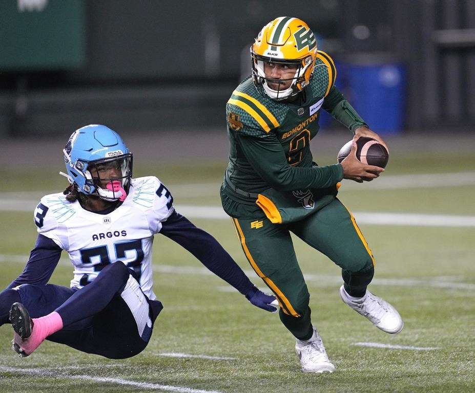 Edmonton Elks quarterback Tre Ford evades a tackle from Toronto Argonauts' Kenneth George Jr. during first half CFL action in Edmonton, on Friday October 25, 2024.