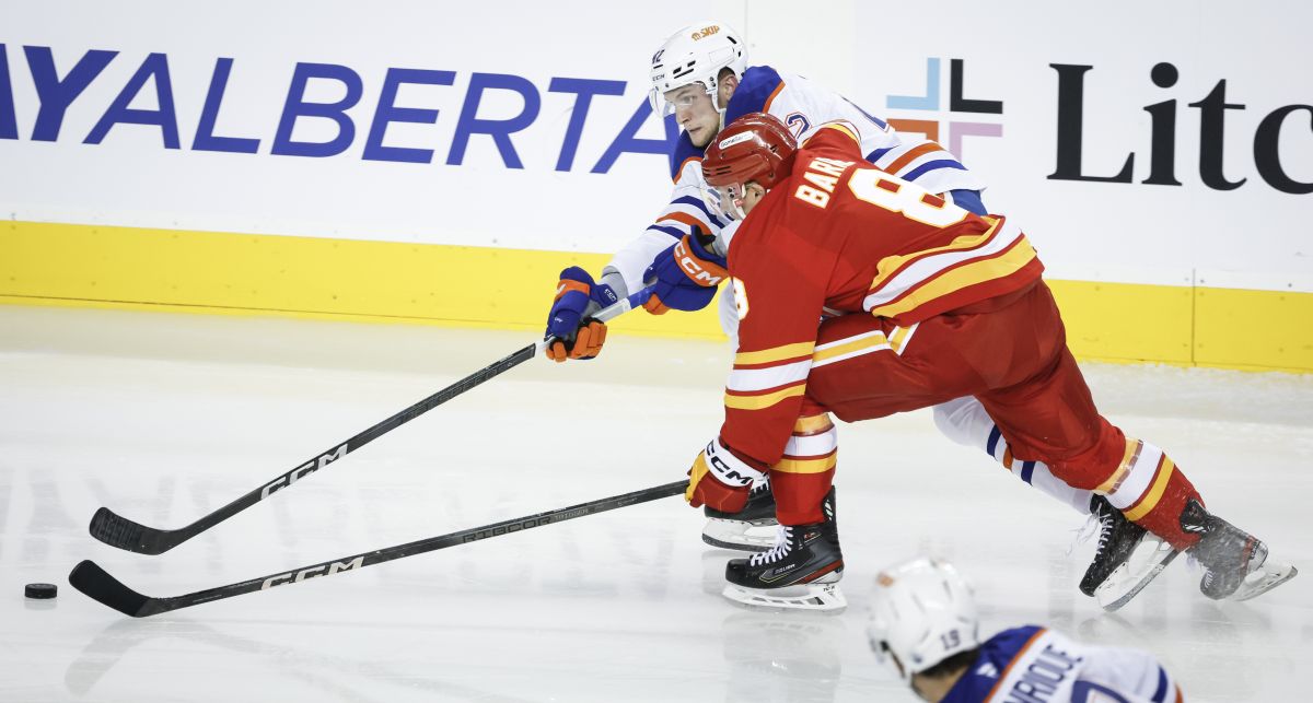 Edmonton Oilers' Jayden Grubbe (42) and Calgary Flames' Tyson Barrie (8) chase a lose puck during second period NHL preseason hockey action in Calgary, Monday, Sept. 23, 2024.