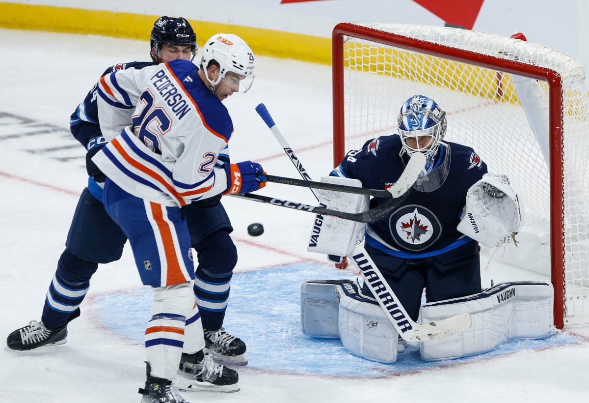 Edmonton Oilers' Lane Pederson (26) tips the puck towards Winnipeg Jets goaltender Kaapo Kahkonen (34) as Dylan Samberg (54) defends during third period NHL pre-season game action in Winnipeg on Wednesday, September 25, 2024. THE CANADIAN PRESS/John Woods.