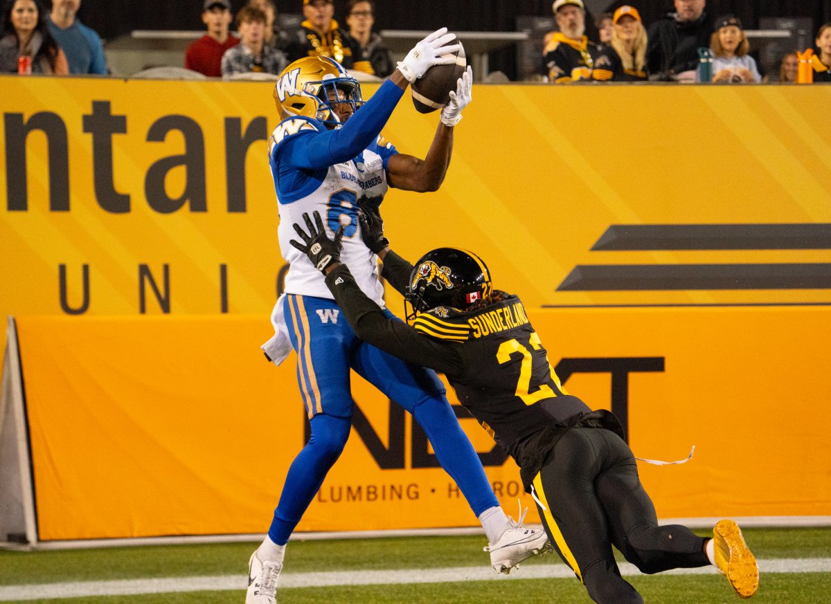 Winnipeg Blue Bombers wide receiver Kevens Clercius (86) makes a touchdown catch while defended by Hamilton Tiger-Cats defensive back Will Sunderland (22) during first half CFL football game action in Hamilton, Ont. on Friday, October 4, 2024. THE CANADIAN PRESS/Peter Power.