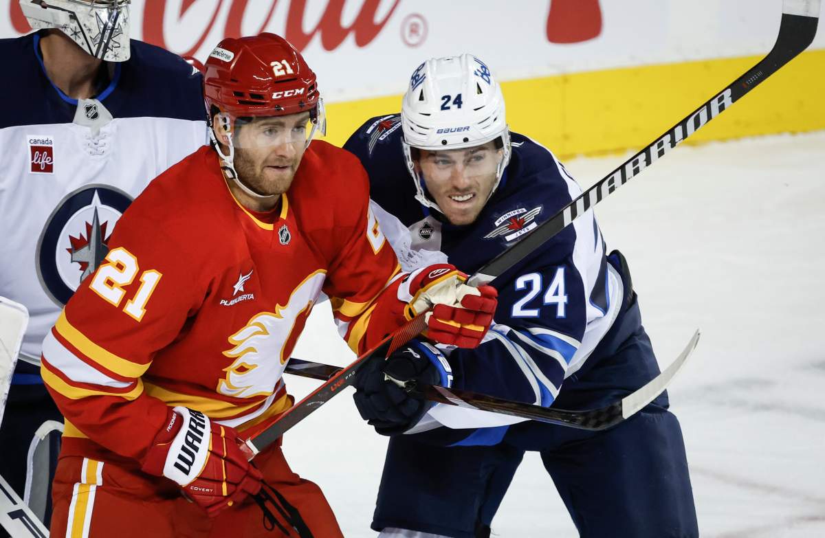 Winnipeg Jets' Haydn Fleury, right, checks Calgary Flames' Kevin Rooney during first period NHL preseason hockey action in Calgary, Alta., Friday, Oct. 4, 2024. 