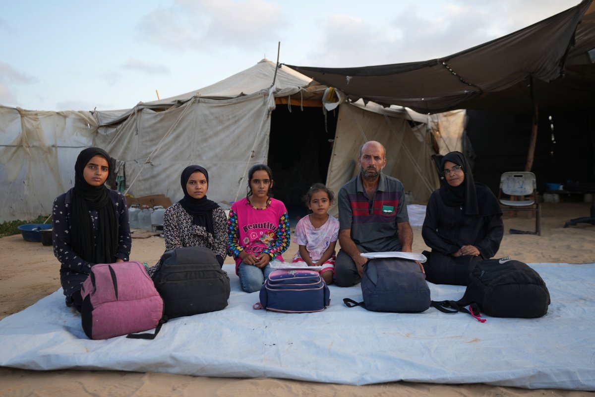 Members of the Abu Jarad family pose for a photo in their tent camp, where they now live after being displaced over five times since the start of the Israel-Hamas war, in Muwasi, Gaza Strip, Friday, Sept. 13, 2024. (AP Photo/Abdel Kareem Hana)