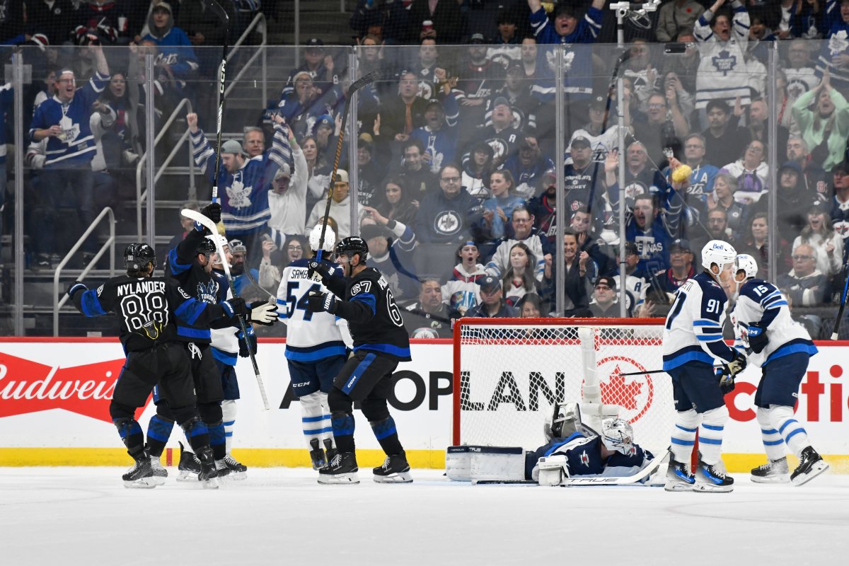 Toronto Maple Leafs' John Tavares celebrates his goal on  Winnipeg Jets' goaltender Connor Hellebuyck with William Nylander (88) and Max Pacioretty (67) during second period NHL hockey action in Winnipeg on Monday, October 28, 2024. THE CANADIAN PRESS/Fred Greenslade.