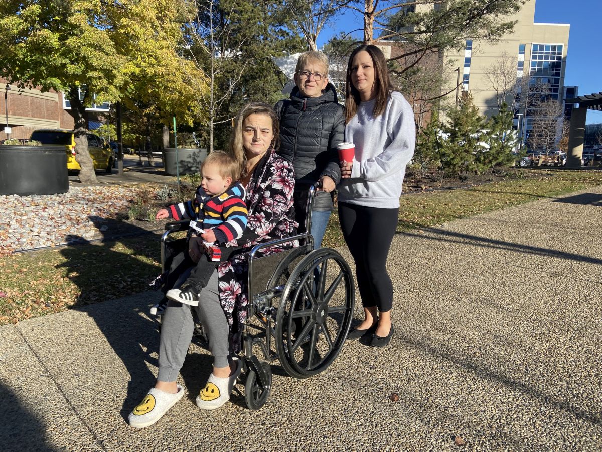 Cassandra Delaney holds her grandson Tatum while sitting on a wheelchair outside an Edmonton hospital. Her mother Jaclyn (second from right) and sister Brianna (far right) stand next to her. Cassandra and Tatum survived a violent crash in north Edmonton on Sunday.