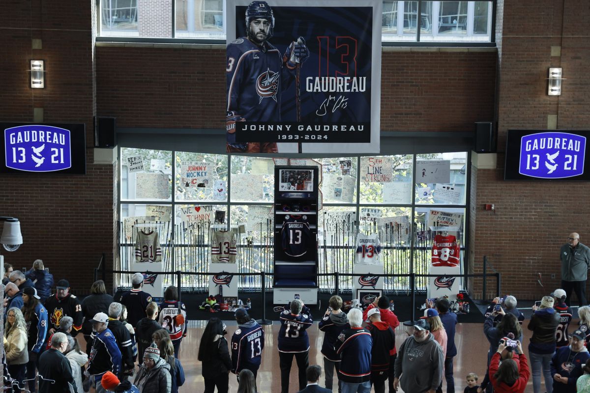 Fans look at a memorial of Columbus Blue Jackets' Johnny Gaudreau and his brother Matthew before the start of an NHL hockey game against the Florida Panthers. Tuesday, Oct. 15, 2024, in Columbus, Ohio.