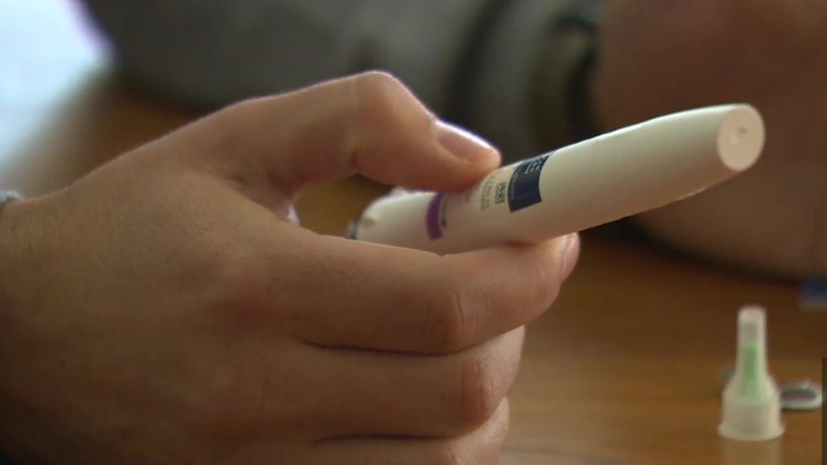 John Jerrett holding his son's Genotropin injection pen.