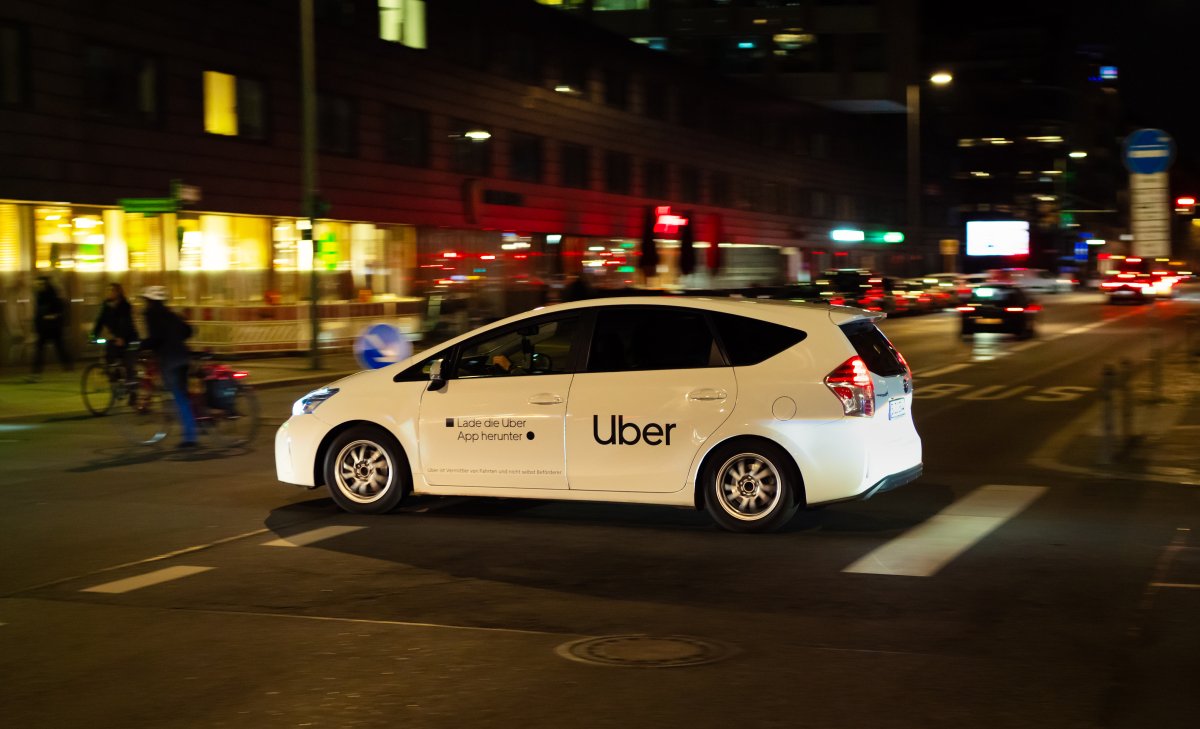 File - A man drives across an intersection after dark in a car labeled "Uber."