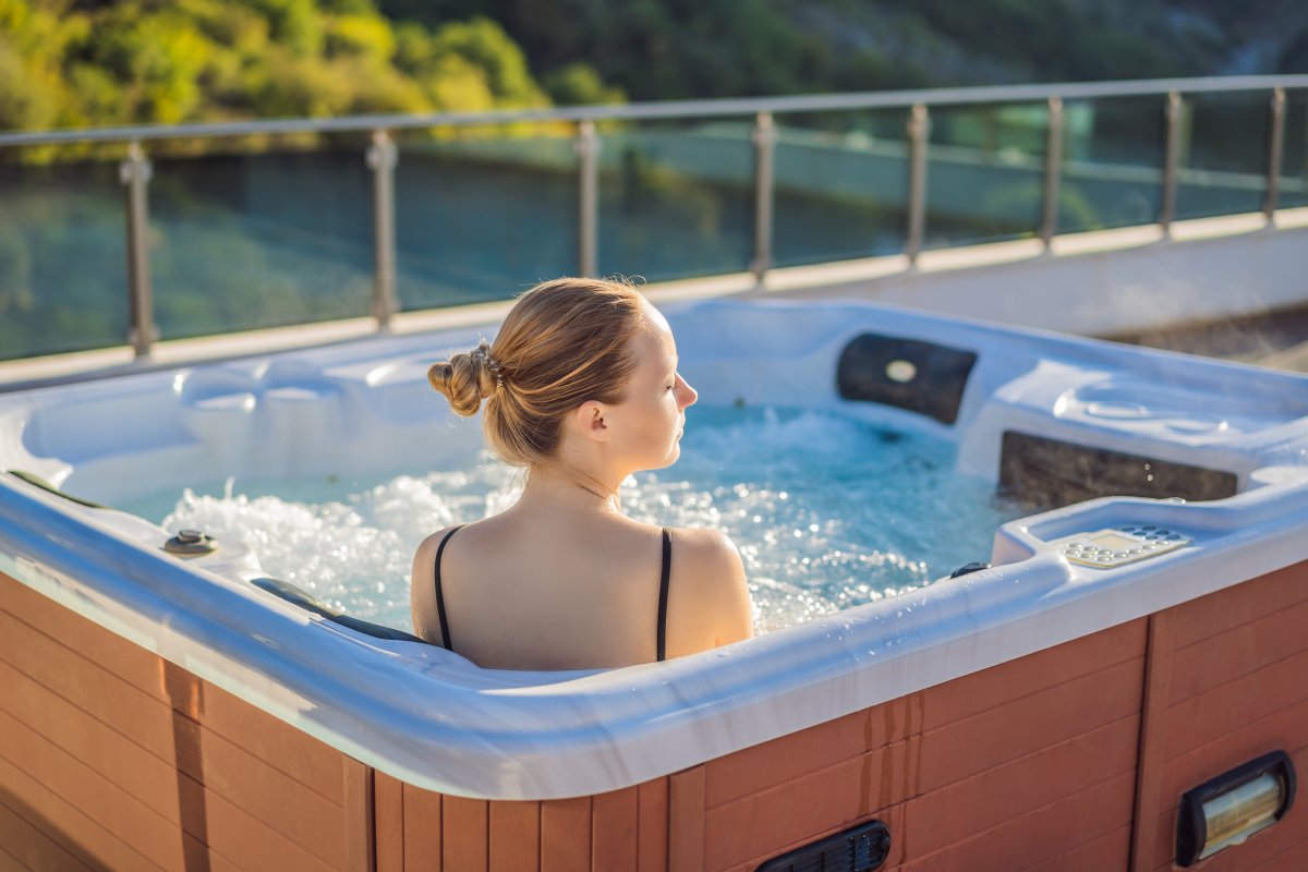 Portrait of young carefree happy smiling woman relaxing at hot tub. Enjoying happy traveling moment vacation. Life against the background of green big mountains.