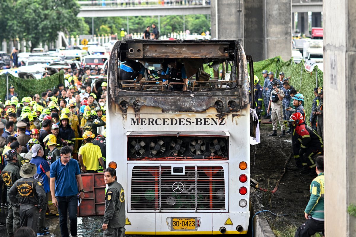 Dozens of resucers and firefighters surround the burned shell of a double-decker bus.