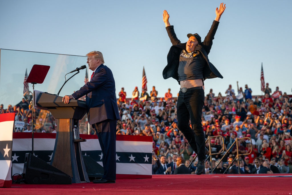 Tesla CEO Elon Musk (R) jumps on stage as he joins former U.S. president and Republican presidential candidate Donald Trump during a campaign rally at the site of his first assassination attempt in Butler, Pa., on Oct. 5, 2024.