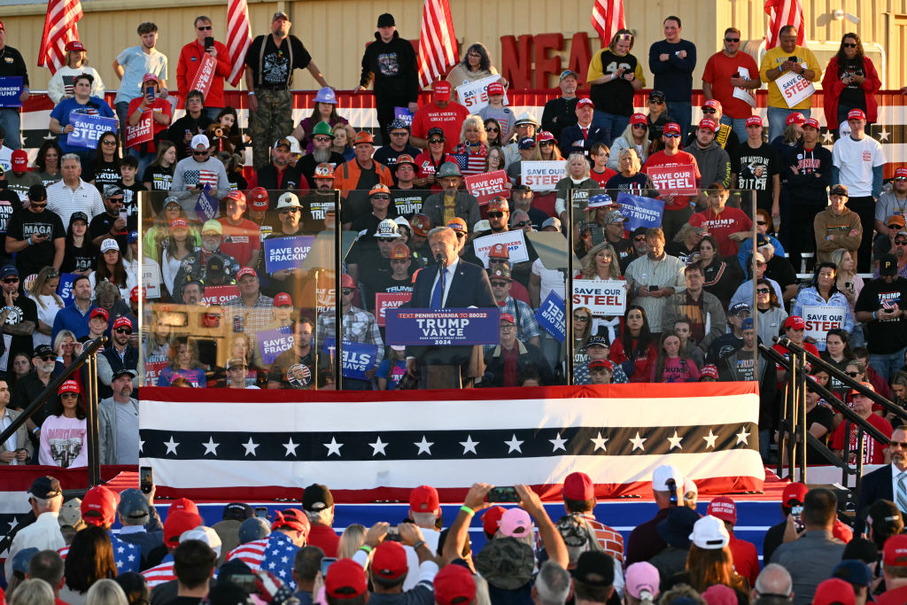 Former U.S. President and Republican presidential candidate Donald Trump speaks behind bulletproof glass during a campaign rally at Arnold Palmer Regional Airport in Latrobe, Pennsylvania, October 19, 2024.