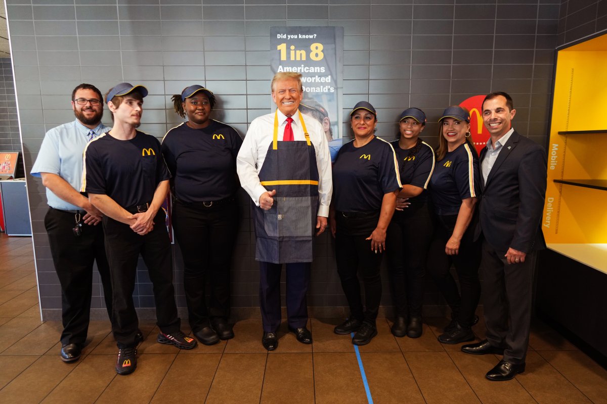 Donald Trump stands between several McDonald's employees in uniform.