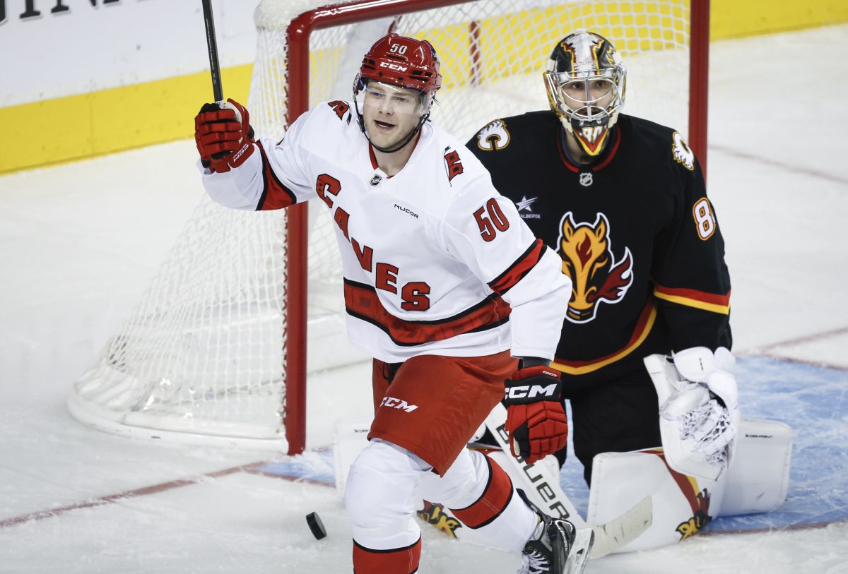 Carolina Hurricanes' Eric Robinson, left, celebrates his team's third goal as Calgary Flames goalie Dan Vladar looks on during second period NHL hockey action in Calgary on Thursday, Oct. 24, 2024.