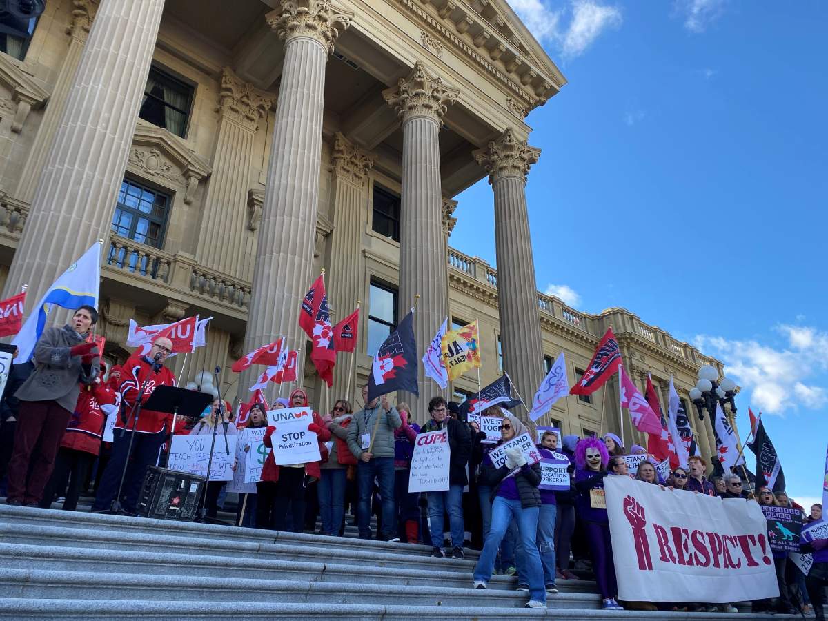 Protesters stand in front of the Alberta legislature on Oct. 24, 2024 to voice their opposition to the provincial government mandating the use of a dispute inquiry board in an ongoing labour dispute between school support workers and the Edmonton Public School Board.