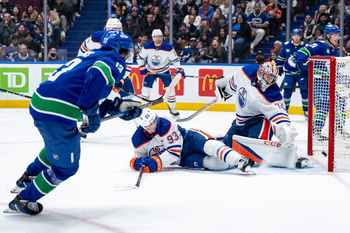 Vancouver Canucks' Arshdeep Bains, left, scores on Edmonton Oilers goaltender Stuart Skinner (74) as Ryan Nugent-Hopkins (93) watches during second period NHL pre-season hockey action in Vancouver, on Friday, October 4, 2024.