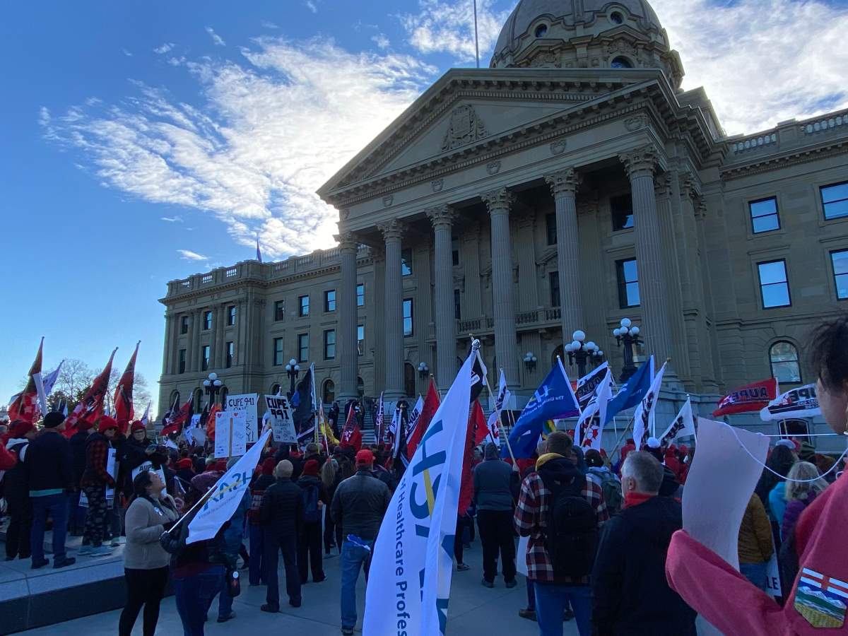 Protesters stand in front of the Alberta legislature on Oct. 24, 2024 to voice their opposition to the provincial government mandating the use of a dispute inquiry board in an ongoing labour dispute between school support workers and the Edmonton Public School Board.