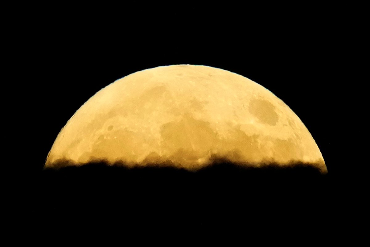 A supermoon rises behind clouds over Larnaca international airport in the eastern Mediterranean island of Cyprus, on Tuesday