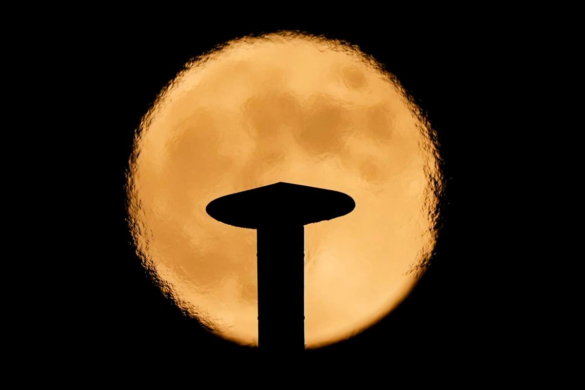 An exhaust pipe from a diesel generator spouts fumes as a supermoon rises, in the background, in Beirut, Lebanon