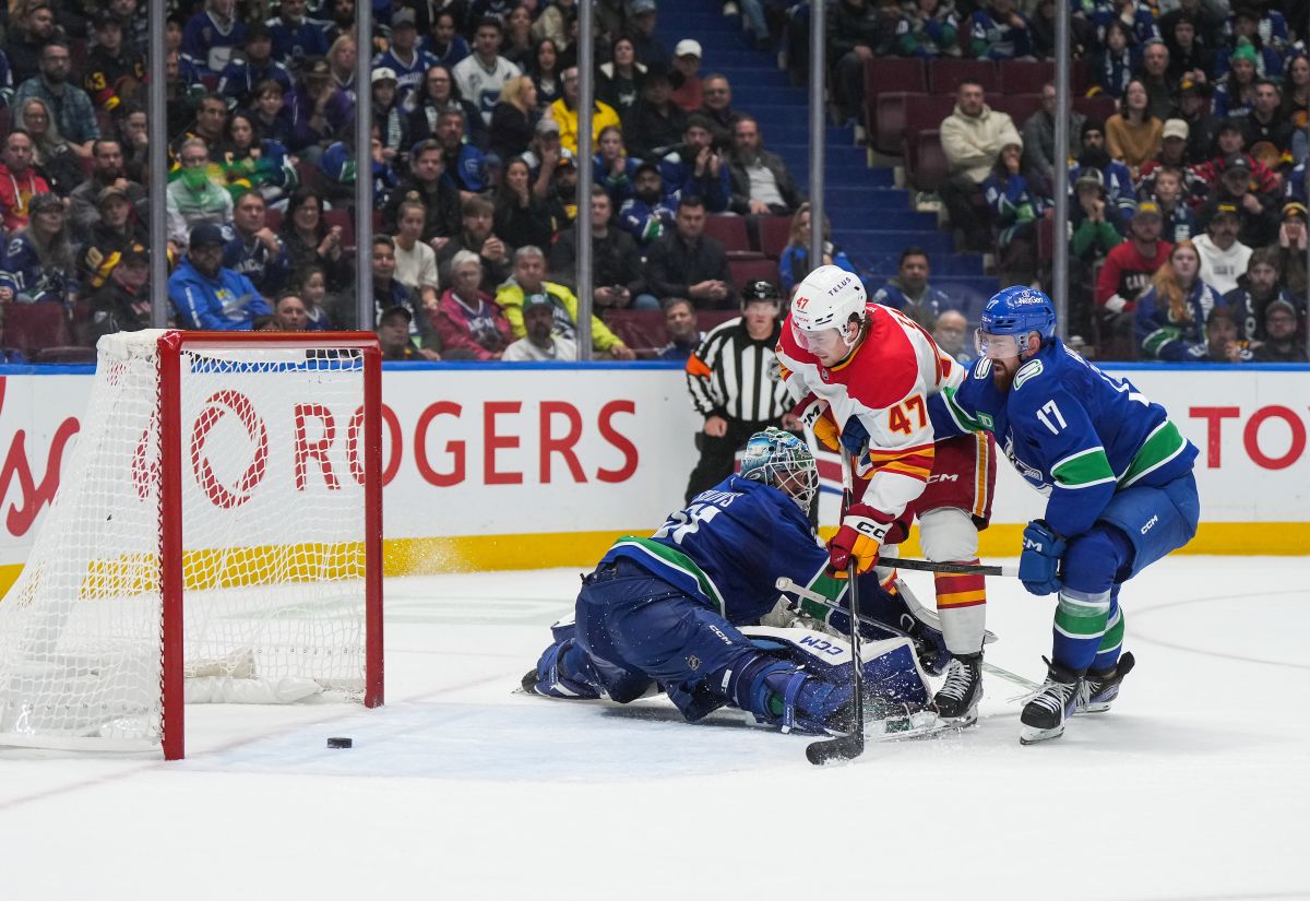 Calgary Flames' Connor Zary (47) scores the winning goal against Vancouver Canucks goalie Arturs Silovs, left, as Filip Hronek (17) defends during overtime NHL hockey action, in Vancouver, on Wednesday, October 9, 2024.
