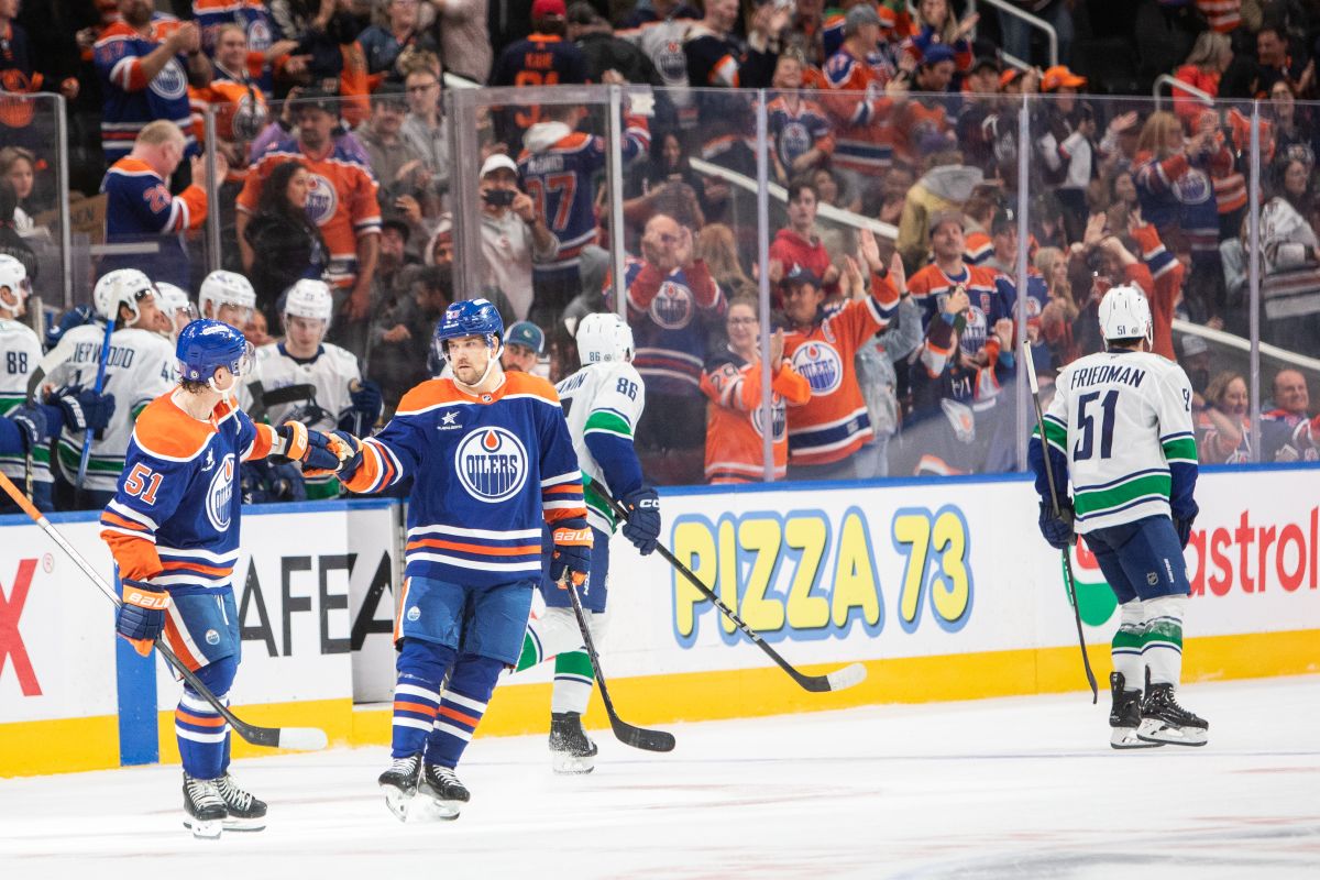 Vancouver Canucks Christian Wolanin (86) and Mark Friedman (51) skate off as Edmonton Oilers Troy Stecher (51) and Viktor Arvidsson (33) celebrates an Oilers win, and Arvidsson's shootout goal, during overtime NHL pre-season action in Edmonton on Monday September 30, 2024.