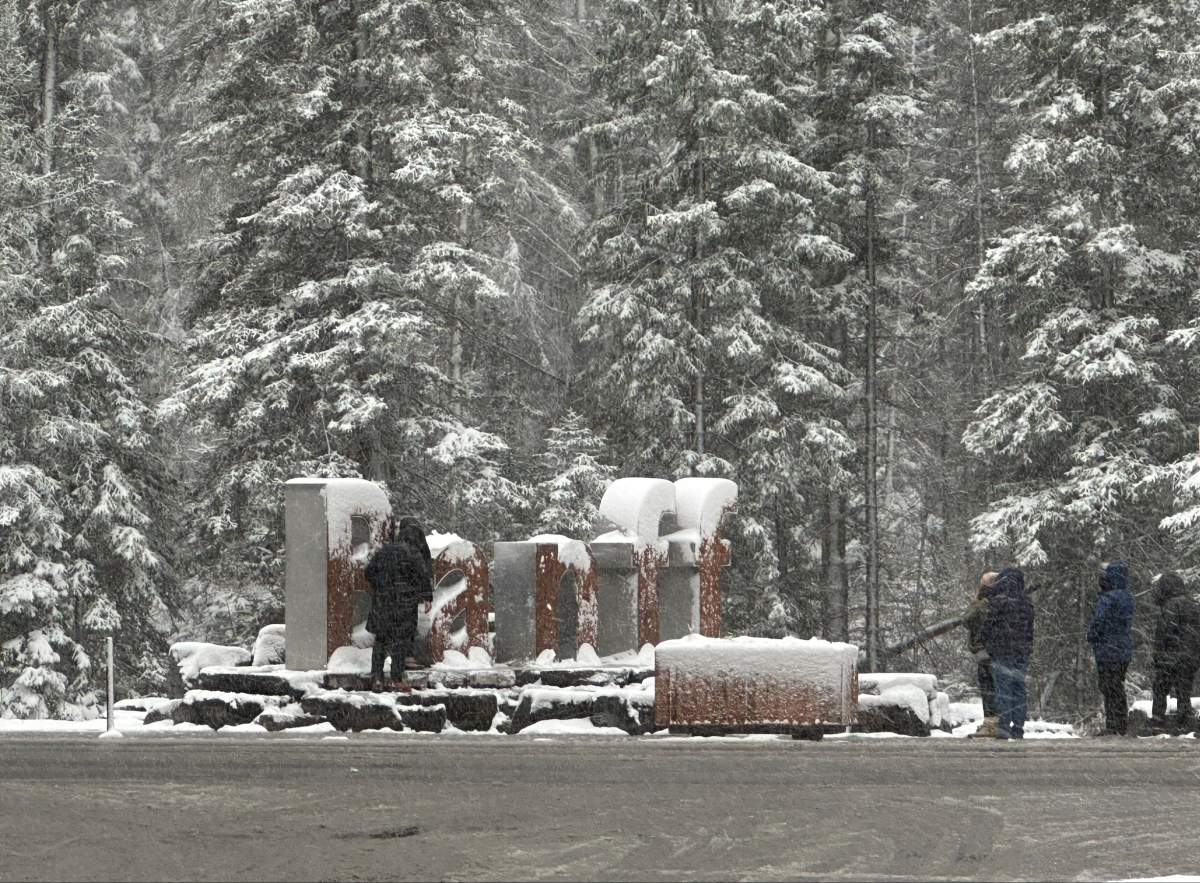 The town of Banff was blanketed in snow Monday afternoon as these tourists posed for photos in front of the famed Banff sign.