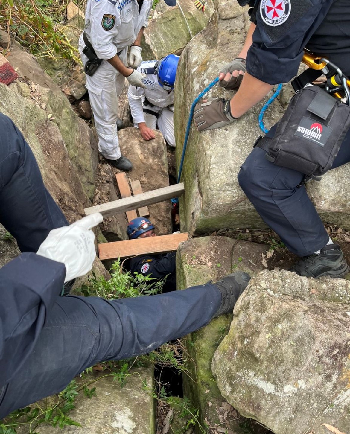 Hardwood, rope and pulleys between two boulders as rescuers work nearby.
