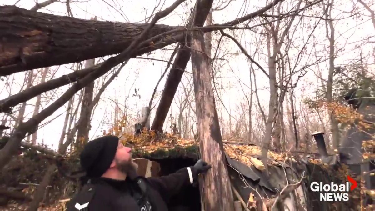 Edmonton Police Service Const. Brett Earley pointing out how the trees and wood used to build the huts could easily fall apart at the encampment in southeast Edmonton.