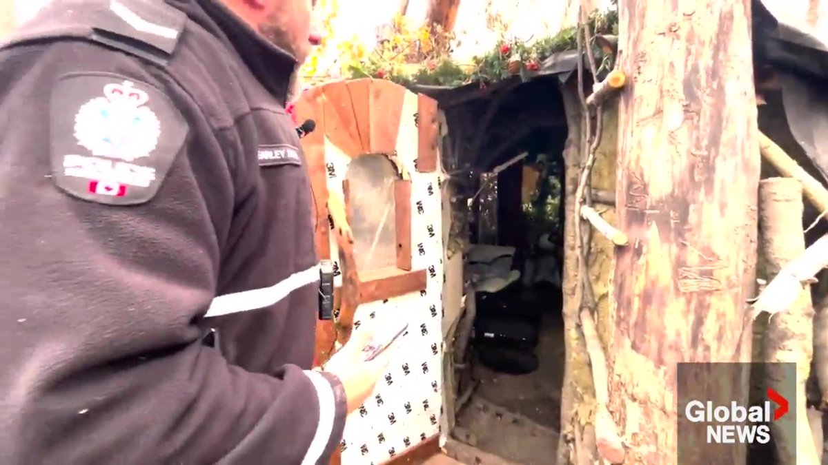 Edmonton Police Service Const. Brett Earley entering one of the huts in the encampment in southeast Edmonton.