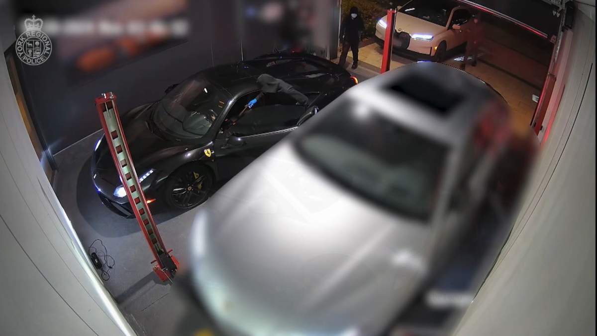 hooded figures enter a ferrari parked in drive way