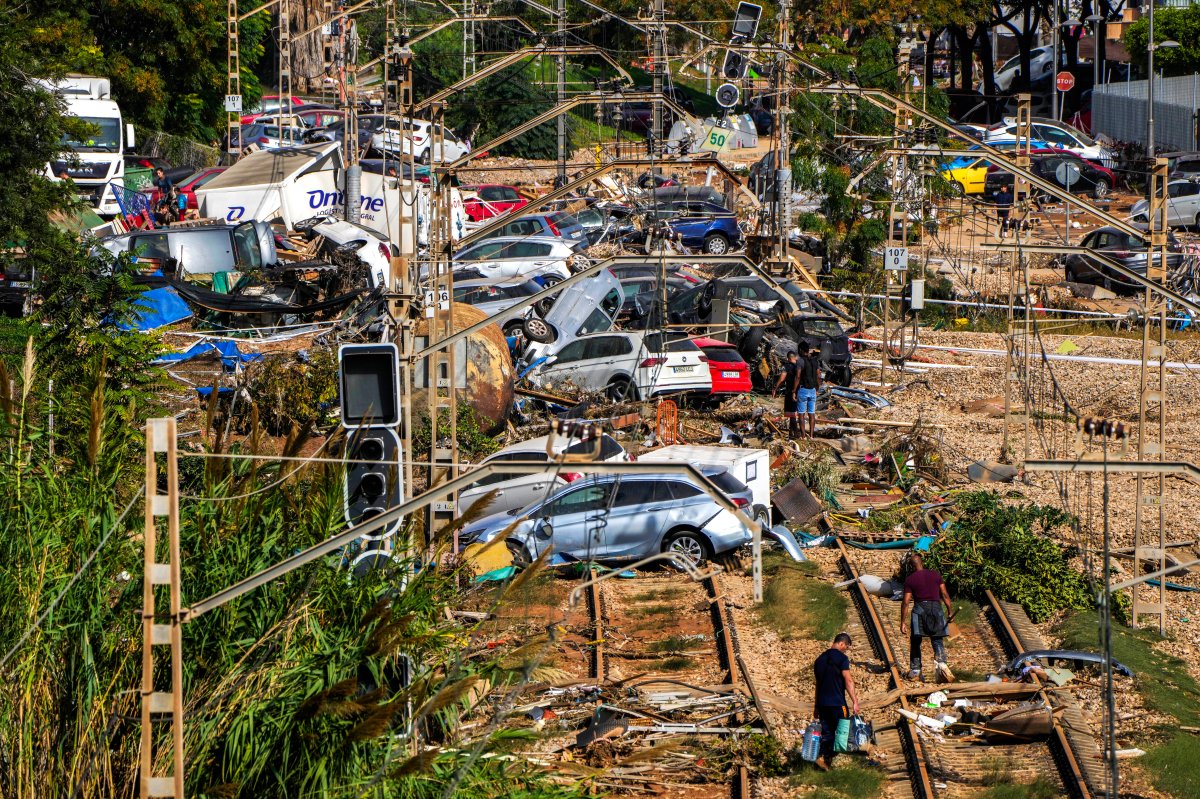 People walk among flooded cars piled up in Valencia, Spain, Thursday, Oct. 31, 2024.