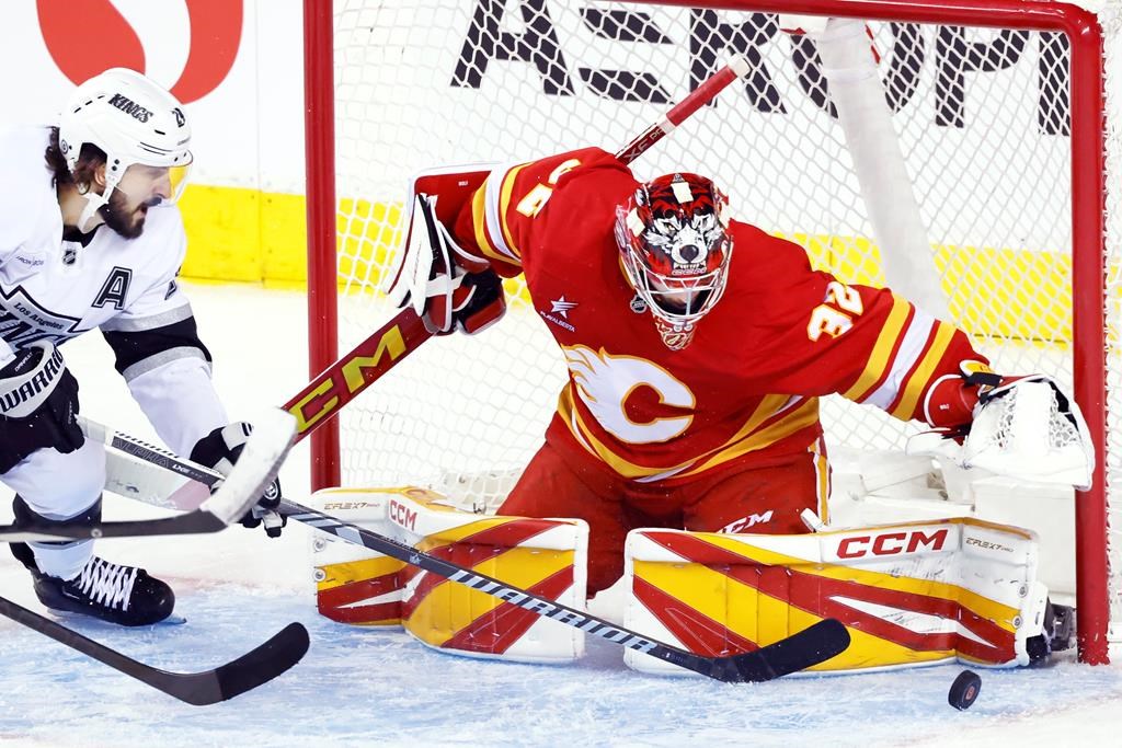 Calgary Flames goalie Dustin Wolf (32) stops a shot by Los Angeles Kings' Phillip Danault during third period NHL hockey action in Calgary, Alta., Monday, Nov. 11, 2024.