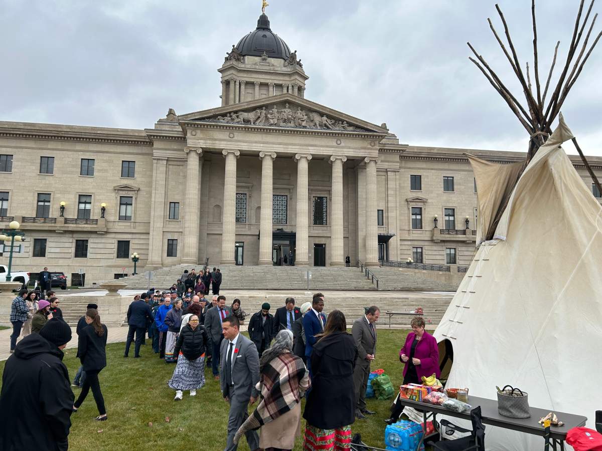 People, including members of the Manitoba NDP caucus, line up outside a tipi in front of the Manitoba legislature Monday, Nov.4, 2024, where a fire was lit to honour Murray Sinclair. The former judge, senator and and chair of the Truth and Reconciliation Commission died Monday at the age of 73. THE CANADIAN PRESS/Steve Lambert