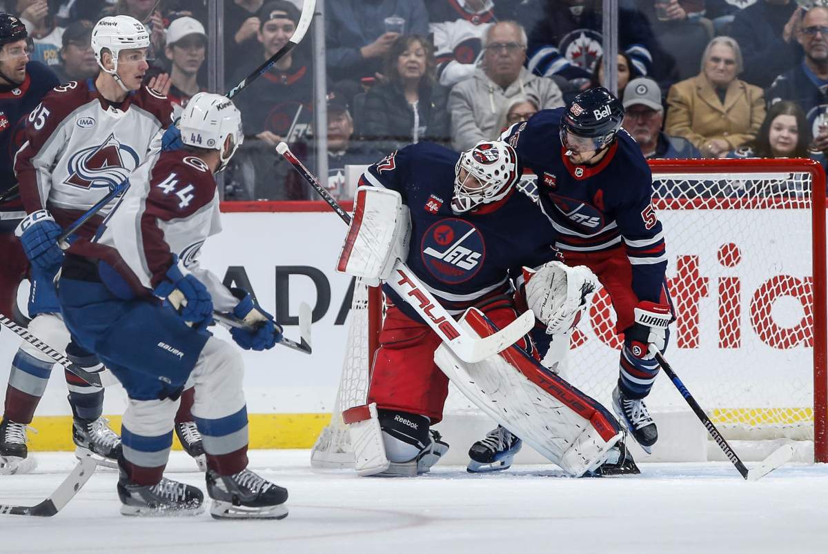 Winnipeg Jets goaltender Connor Hellebuyck (37) saves the shot from Colorado Avalanche's Calvin de Haan (44) as Mark Scheifele (55) defends during second period NHL action in Winnipeg on Thursday, November 7, 2024. THE CANADIAN PRESS/John Woods.