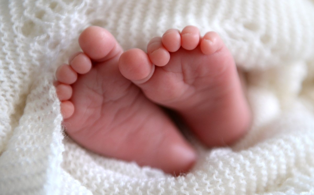 new born baby's feet peeking out of a shawl,