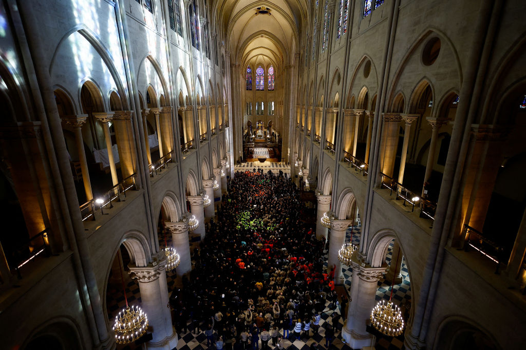 Attendees including workers of reconstruction of Notre-Dame de Paris cathedral gather during a speech by French President Emmanuel Macron (C) in the nave of the cathedral in Paris, on November 29, 2024. The Notre-Dame Cathedral is set to re-open early December 2024, with a planned weekend of ceremonies on December 7 and 8, 2024, five years after the 2019 fire which ravaged the world heritage landmark and toppled its spire.