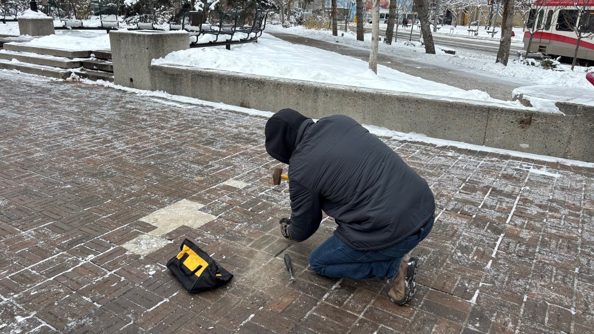 A man chips at an Olympic Plaza brick.