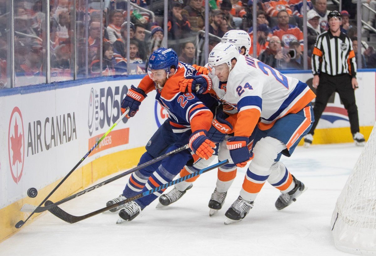 New York Islanders' Scott Mayfield (24) and Grant Hutton (hidden) battle Edmonton Oilers' Leon Draisaitl (29) for the puck during second period NHL action in Edmonton on Tuesday Nov. 12, 2024. THE CANADIAN PRESS/Amber Bracken AMBER BRACKEN