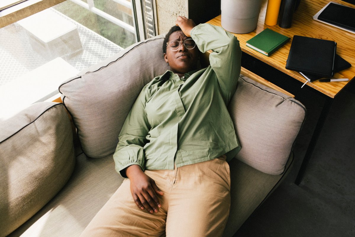 A businesswoman lying on a couch with her hand on her forehead. 