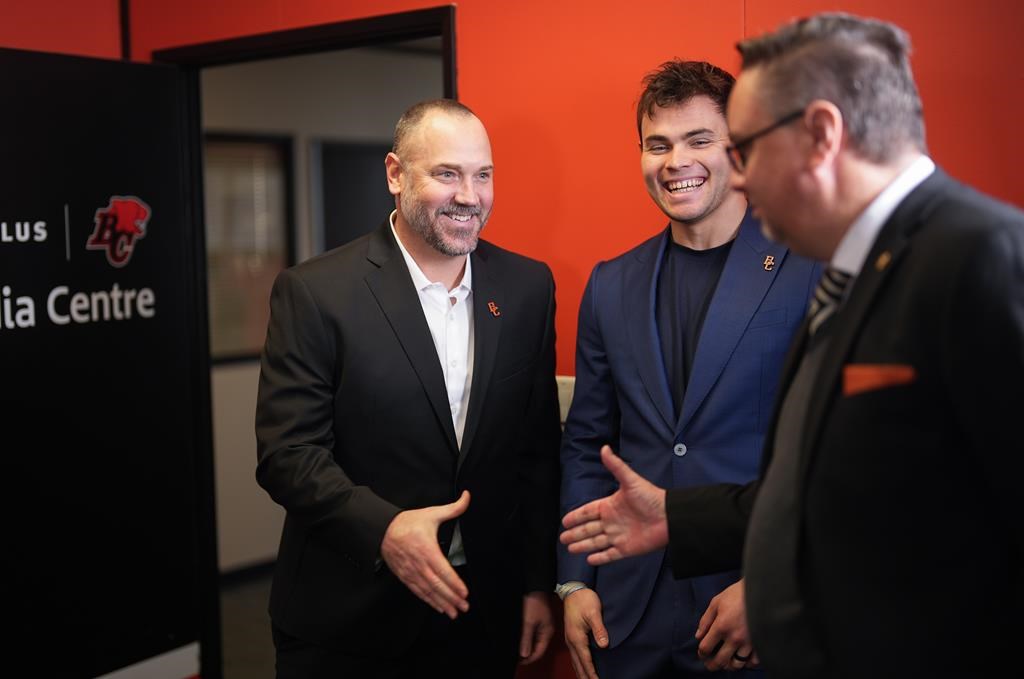 New B.C. Lions head coach Buck Pierce, left, reaches to shake hands with co-general manager and director of football operations Neil McEvoy, right, as quarterback Nathan Rourke watches after a news conference at the CFL football team's practice facility, in Surrey, B.C., Wednesday, Dec. 4, 2024. THE CANADIAN PRESS/Darryl Dyck.