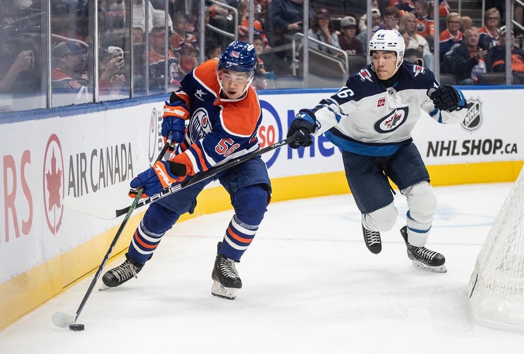 Winnipeg Jets' Kevin He, right, and Edmonton Oilers' William Nicholl (56) battle for the puck during second-period NHL preseason action in Edmonton, Sunday, Sept. 22, 2024. 
Forward Kevin He has agreed to a three-year, entry-level contract with the Jets, making him the first Chinese-born player to sign an NHL contract.THE CANADIAN PRESS/Jason Franson.