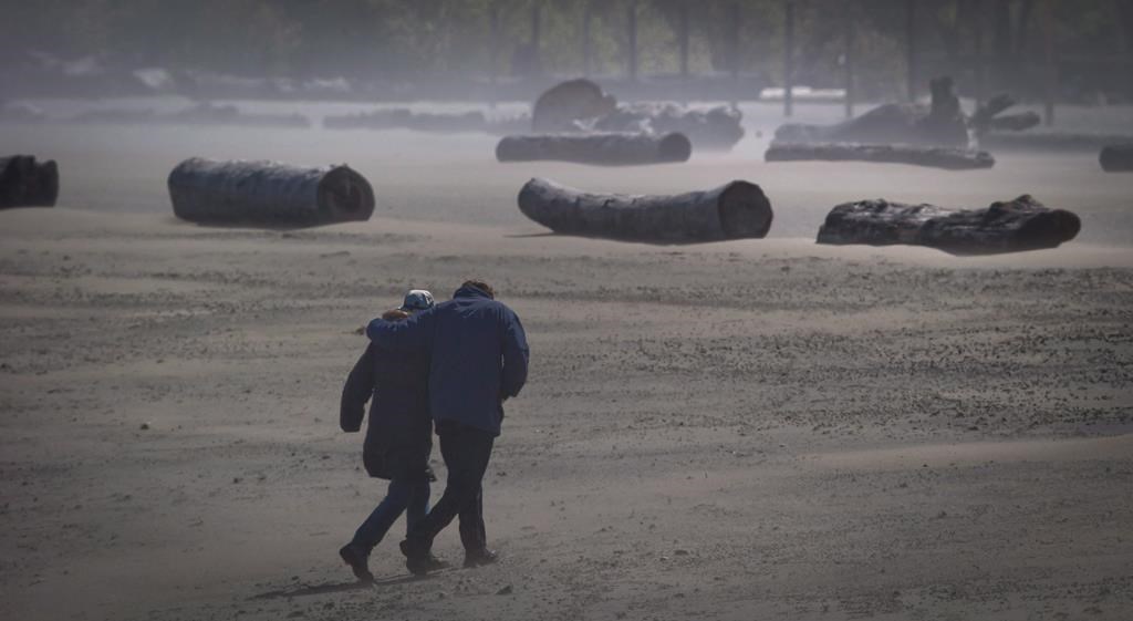 High winds whip up sand as a couple walks along Spanish Banks Beach in Vancouver.