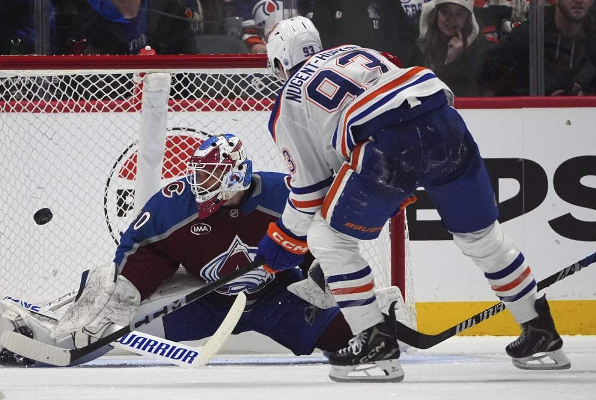 Edmonton Oilers center Ryan Nugent-Hopkins, front, puts a shot on Colorado Avalanche goaltender Alexandar Georgiev in the third period of an NHL hockey game Saturday, Nov. 30, 2024, in Denver. (AP Photo/David Zalubowski).