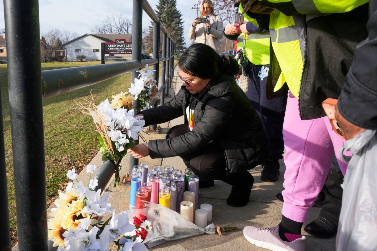 A resident places some flowers outside the Abundant Life Christian School Tuesday, Dec. 17, 2024 in Madison, Wis., following a shooting on Monday.