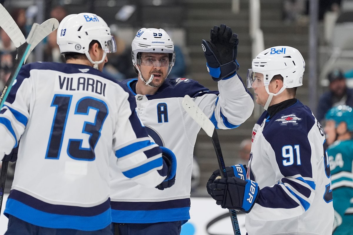 Winnipeg Jets center Mark Scheifele, center, celebrates with teammates Gabriel Vilardi (13) and Cole Perfetti (91) after scoring a goal against the San Jose Sharks during the second period of an NHL hockey game in San Jose, Calif., Tuesday, Dec. 17, 2024. (AP Photo/Tony Avelar).