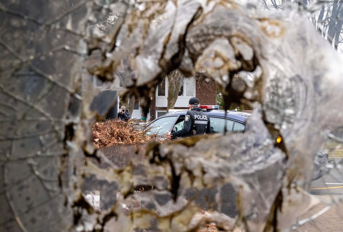 Police are seen through the broken windows in the doors of Congregation Beth Tikvah, as police investigate alleged arson at the synagogue in the suburb of Dollard-des-Ormeaux in Montreal, Wednesday, Dec.18, 2024.