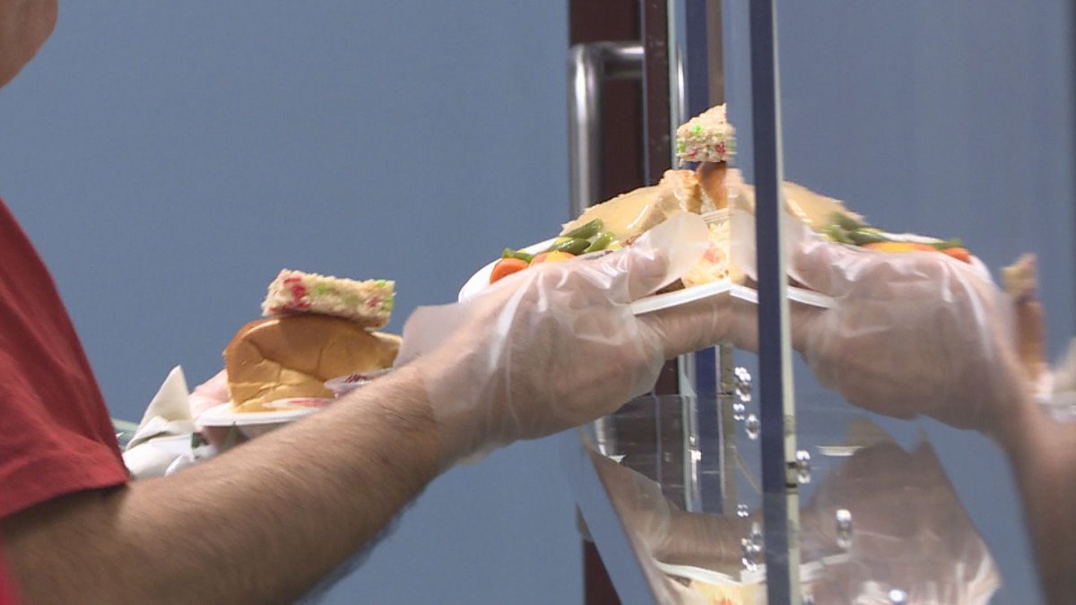 A volunteer at Siloam Mission gets a plate of Christmas lunch from the kitchen to serve someone in need.